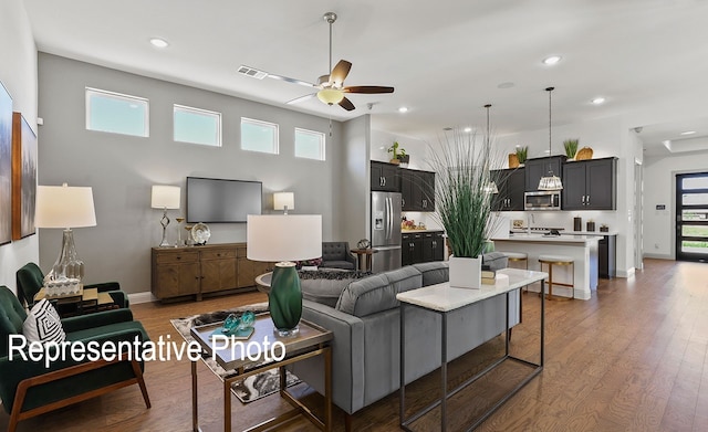 living room with dark wood-type flooring, a wealth of natural light, and ceiling fan