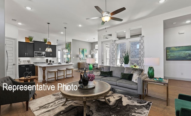 living room with dark hardwood / wood-style flooring, ceiling fan, and a healthy amount of sunlight