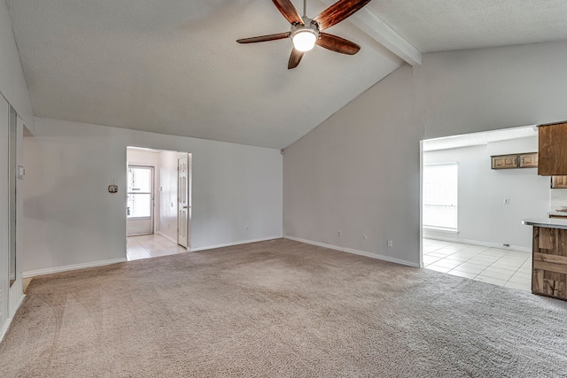 unfurnished living room with a textured ceiling, lofted ceiling with beams, light colored carpet, and ceiling fan