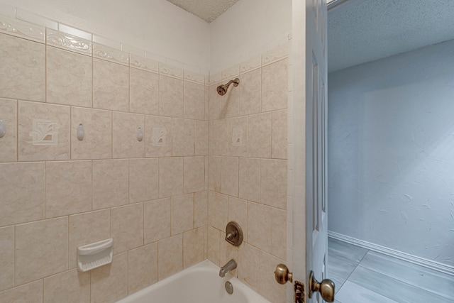 bathroom with a textured ceiling and tiled shower / bath