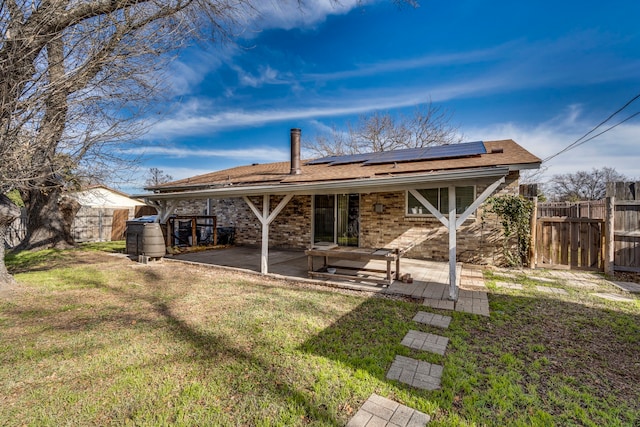 rear view of property with solar panels, a patio, and a lawn