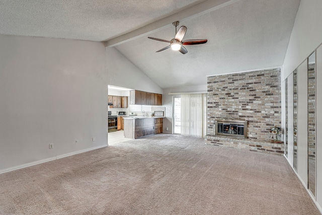 unfurnished living room featuring ceiling fan, a textured ceiling, a fireplace, beam ceiling, and light colored carpet