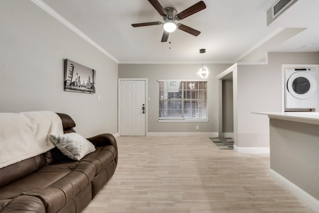 living room featuring ceiling fan, crown molding, light wood-type flooring, and stacked washer / drying machine