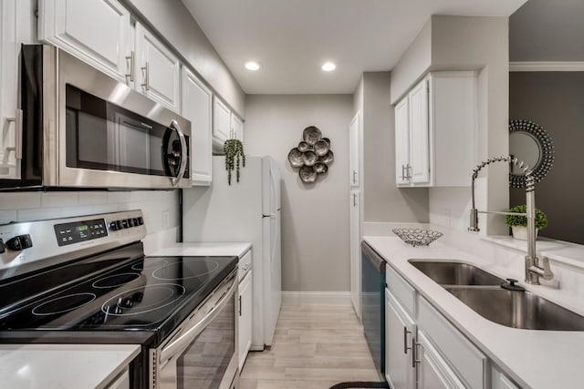 kitchen featuring white cabinets, appliances with stainless steel finishes, light hardwood / wood-style floors, and backsplash