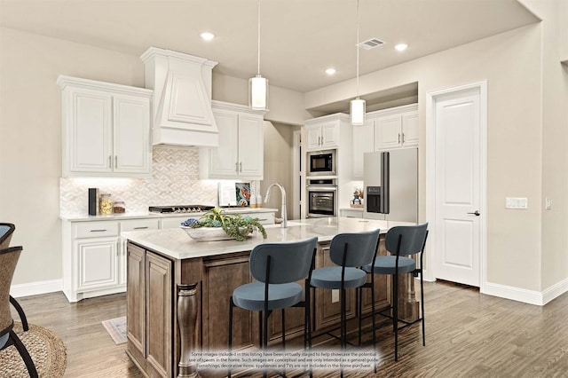 kitchen with visible vents, a breakfast bar, wood finished floors, stainless steel appliances, and light countertops