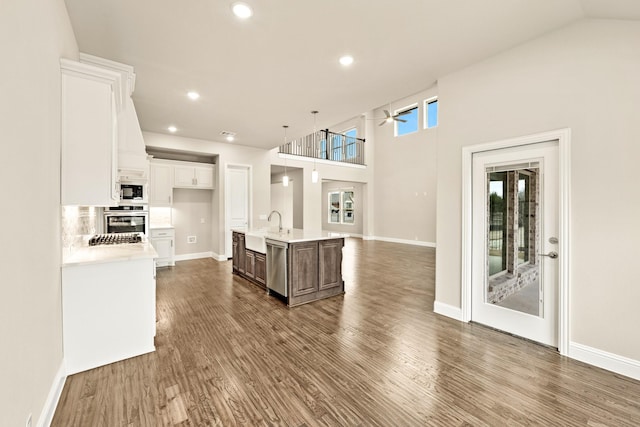 kitchen with stainless steel appliances, light countertops, dark wood-type flooring, white cabinets, and a sink