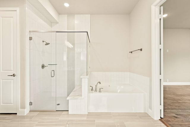 full bathroom featuring a stall shower, wood finished floors, and a bath