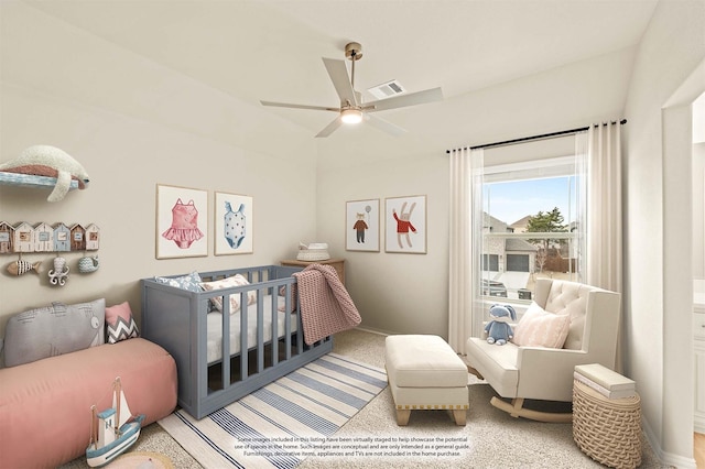 carpeted bedroom featuring a crib, ceiling fan, and visible vents