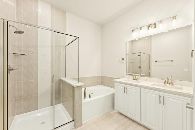 full bathroom featuring a stall shower, double vanity, a sink, and a bath