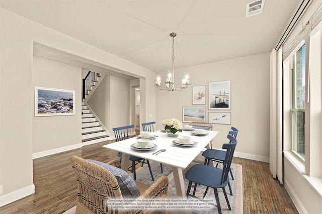 dining space with a notable chandelier, dark wood-type flooring, visible vents, baseboards, and stairway