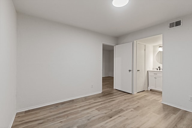 unfurnished bedroom featuring light wood-type flooring and ensuite bath