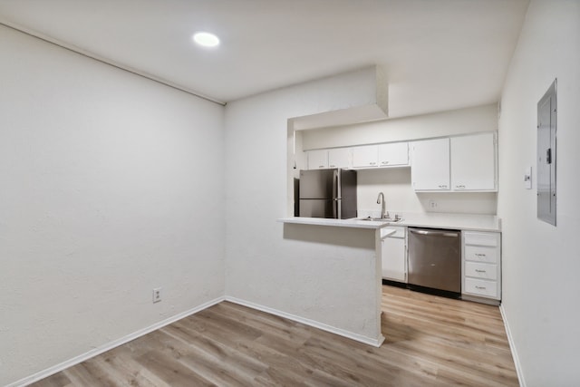 kitchen with light hardwood / wood-style floors, white cabinetry, sink, kitchen peninsula, and appliances with stainless steel finishes