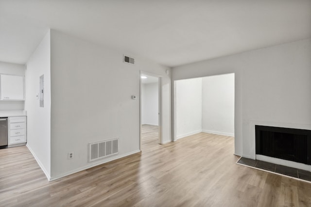 unfurnished living room featuring light wood-type flooring and electric panel