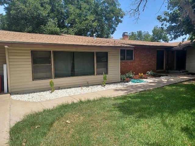 rear view of property featuring a lawn