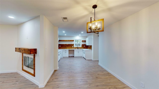 hallway featuring an inviting chandelier, sink, and light hardwood / wood-style flooring