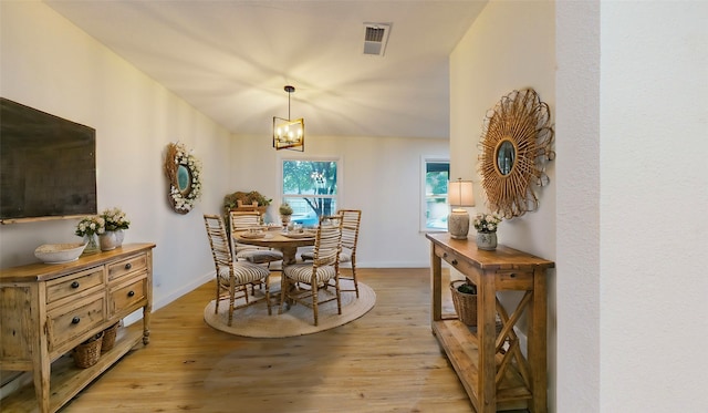 dining space featuring lofted ceiling, an inviting chandelier, and light hardwood / wood-style flooring