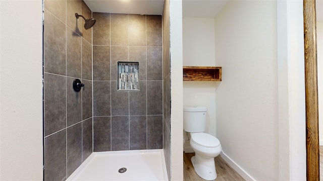 bathroom with tiled shower, wood-type flooring, and toilet