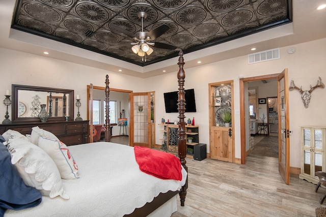 bedroom with a tray ceiling, multiple windows, and french doors