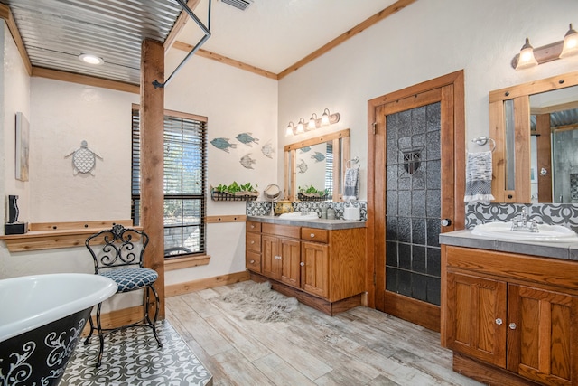 bathroom featuring decorative backsplash, a bathtub, ornamental molding, vanity, and hardwood / wood-style flooring