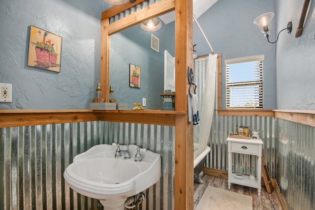 bathroom with wood-type flooring, shower / tub combo with curtain, and sink