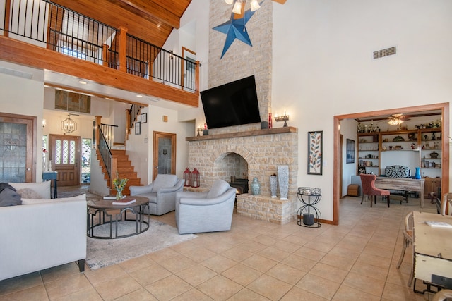 living room with wooden ceiling, ceiling fan with notable chandelier, a brick fireplace, a towering ceiling, and light tile patterned floors