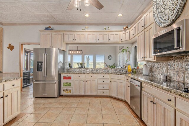 kitchen with appliances with stainless steel finishes, light tile patterned floors, ornamental molding, and sink