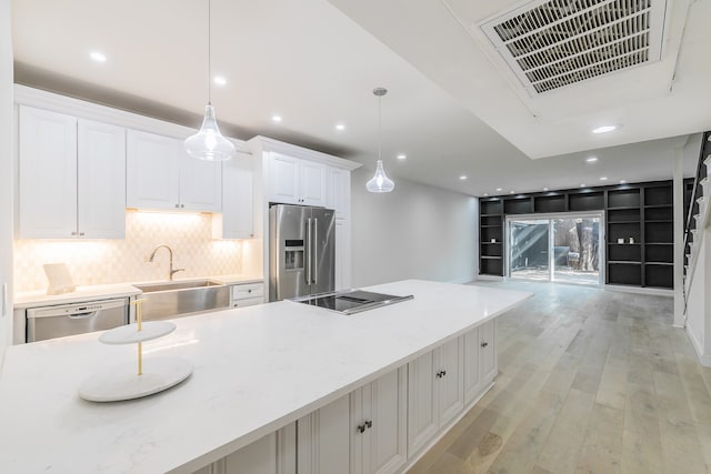 kitchen featuring white cabinetry, sink, stainless steel appliances, light hardwood / wood-style flooring, and decorative light fixtures