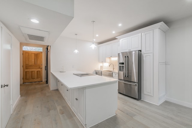 kitchen with kitchen peninsula, appliances with stainless steel finishes, light wood-type flooring, white cabinetry, and hanging light fixtures