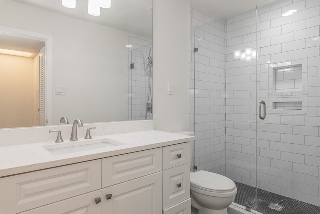 bathroom with vanity, toilet, and a shower with door