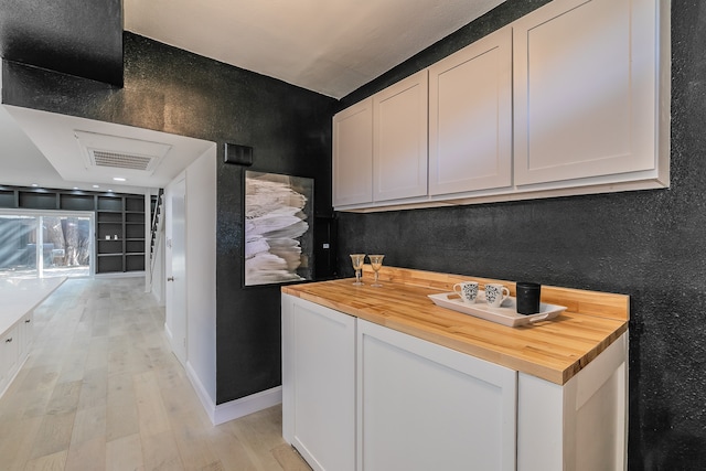 kitchen featuring butcher block counters, white cabinetry, and light hardwood / wood-style flooring