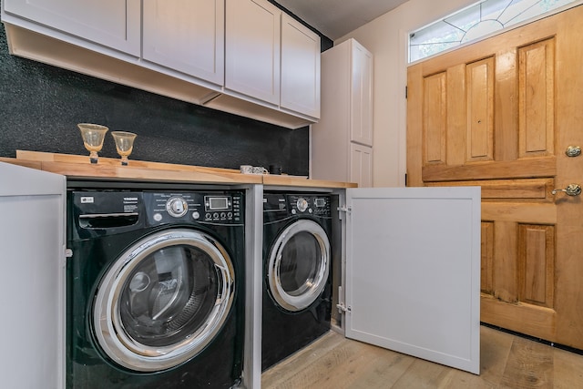 laundry room with washing machine and clothes dryer, cabinets, and light hardwood / wood-style floors