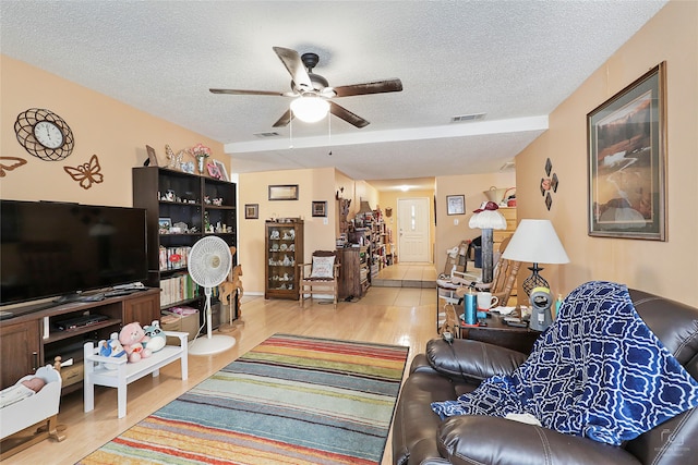 living room featuring ceiling fan, a textured ceiling, and light hardwood / wood-style flooring