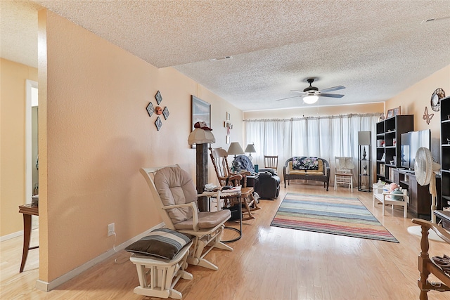 sitting room with ceiling fan, a textured ceiling, and light hardwood / wood-style flooring