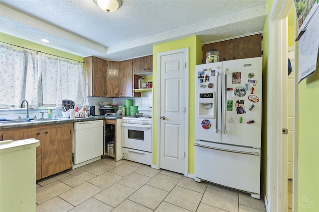 kitchen featuring light tile patterned floors, a textured ceiling, sink, backsplash, and white appliances