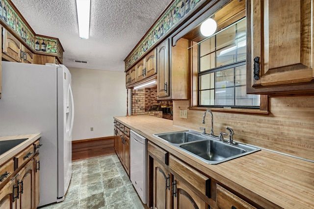 kitchen featuring a textured ceiling, decorative backsplash, sink, and white appliances