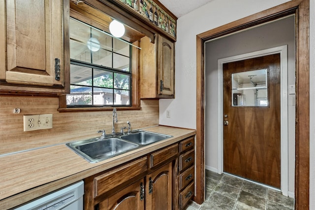 kitchen featuring a textured ceiling, sink, dishwashing machine, and tasteful backsplash