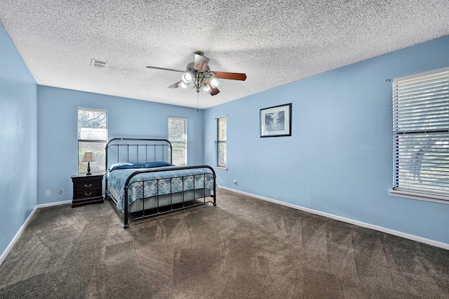 bedroom with a textured ceiling, dark colored carpet, and ceiling fan