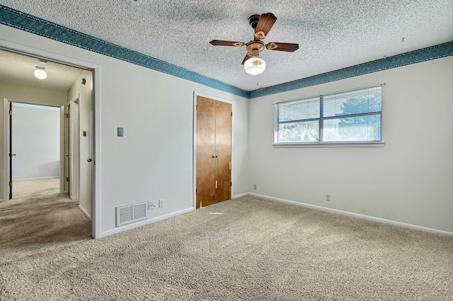 unfurnished bedroom featuring ceiling fan, a textured ceiling, and carpet flooring