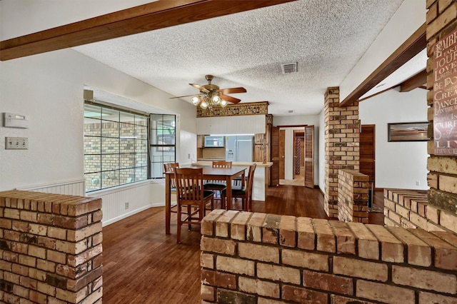 dining room featuring dark hardwood / wood-style flooring, beamed ceiling, and a textured ceiling