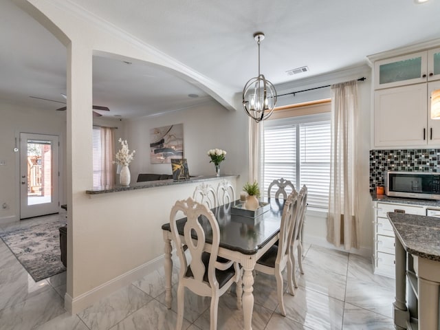 dining space with ornamental molding and ceiling fan with notable chandelier