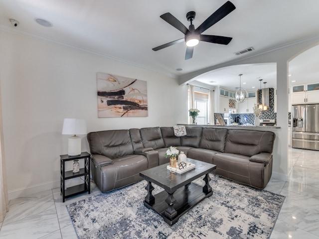 living room featuring ornamental molding and ceiling fan with notable chandelier