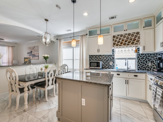 kitchen featuring dark stone counters, hanging light fixtures, decorative backsplash, and a center island