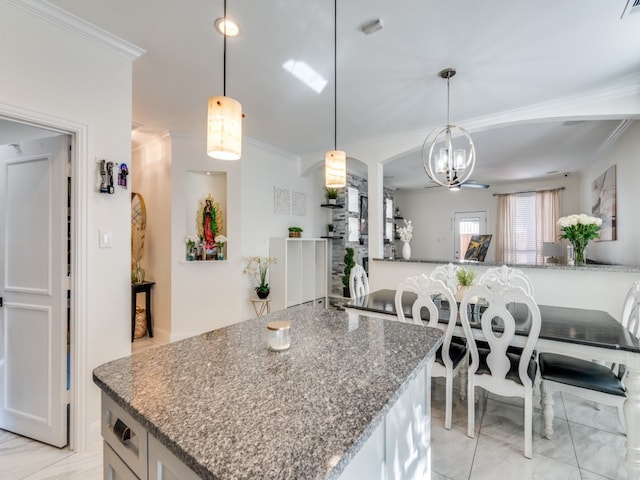 kitchen with dark stone countertops, hanging light fixtures, a notable chandelier, and crown molding