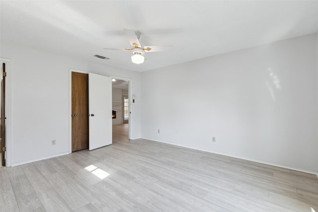 empty room with ceiling fan and light hardwood / wood-style flooring