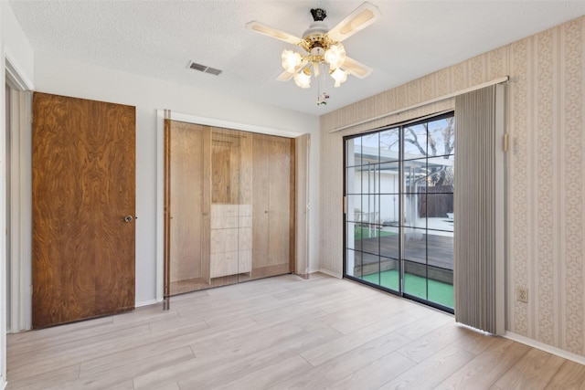 unfurnished bedroom featuring ceiling fan, a textured ceiling, access to outside, and light wood-type flooring