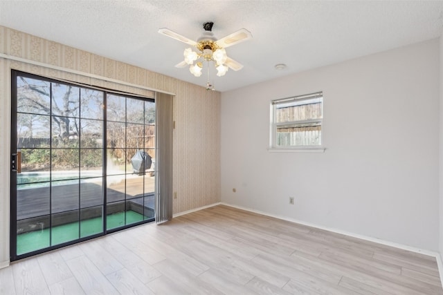 empty room featuring ceiling fan, light hardwood / wood-style floors, and a textured ceiling