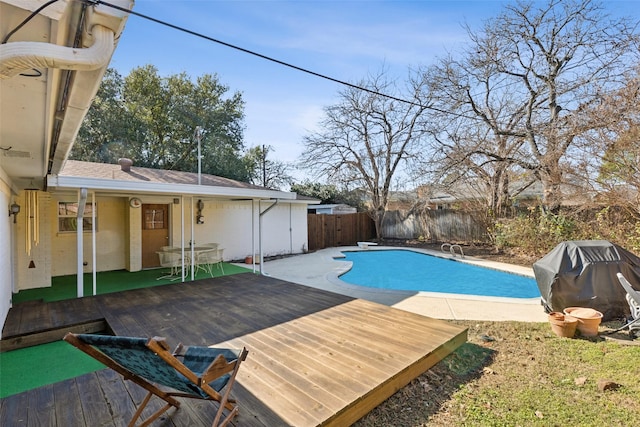 view of swimming pool featuring a wooden deck and grilling area