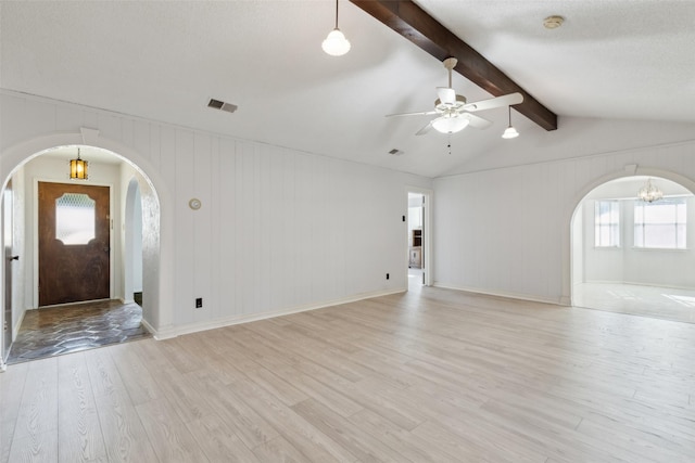 foyer entrance featuring ceiling fan with notable chandelier, a textured ceiling, wood walls, lofted ceiling with beams, and light hardwood / wood-style flooring