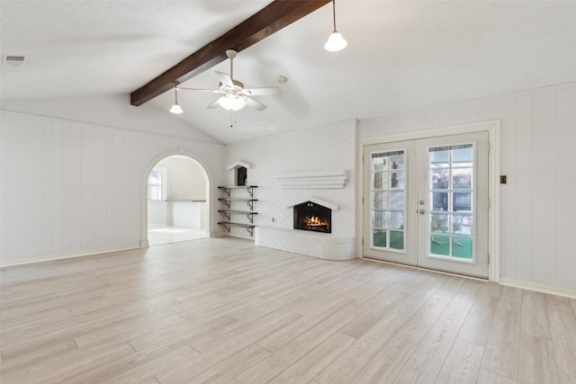 unfurnished living room with a textured ceiling, french doors, a fireplace, ceiling fan, and light hardwood / wood-style flooring