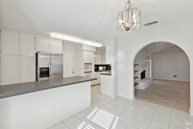 kitchen with white appliances, decorative light fixtures, white cabinetry, an inviting chandelier, and light tile patterned flooring